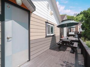 A wooden deck with picnic tables and an umbrella, a garage door, and a window. - Hongcheon Daebakine Pension (Hongcheon)
