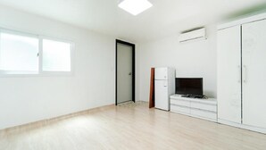 A room with a large window, a door, a white wardrobe, a small white cabinet, and a flat-screen TV on a white dresser. - Hongcheon Daebakine Pension (Hongcheon)