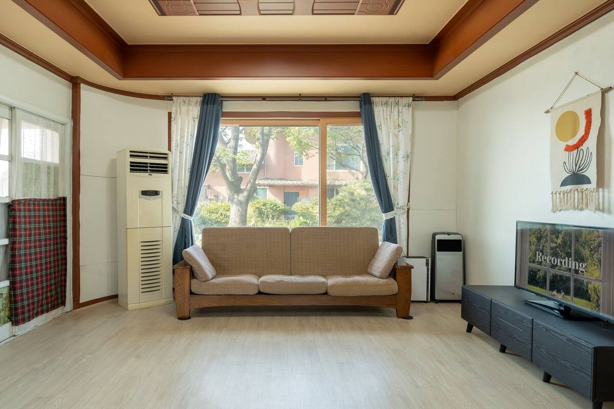 A living room with a sofa, a television, and a wall-mounted decoration.
