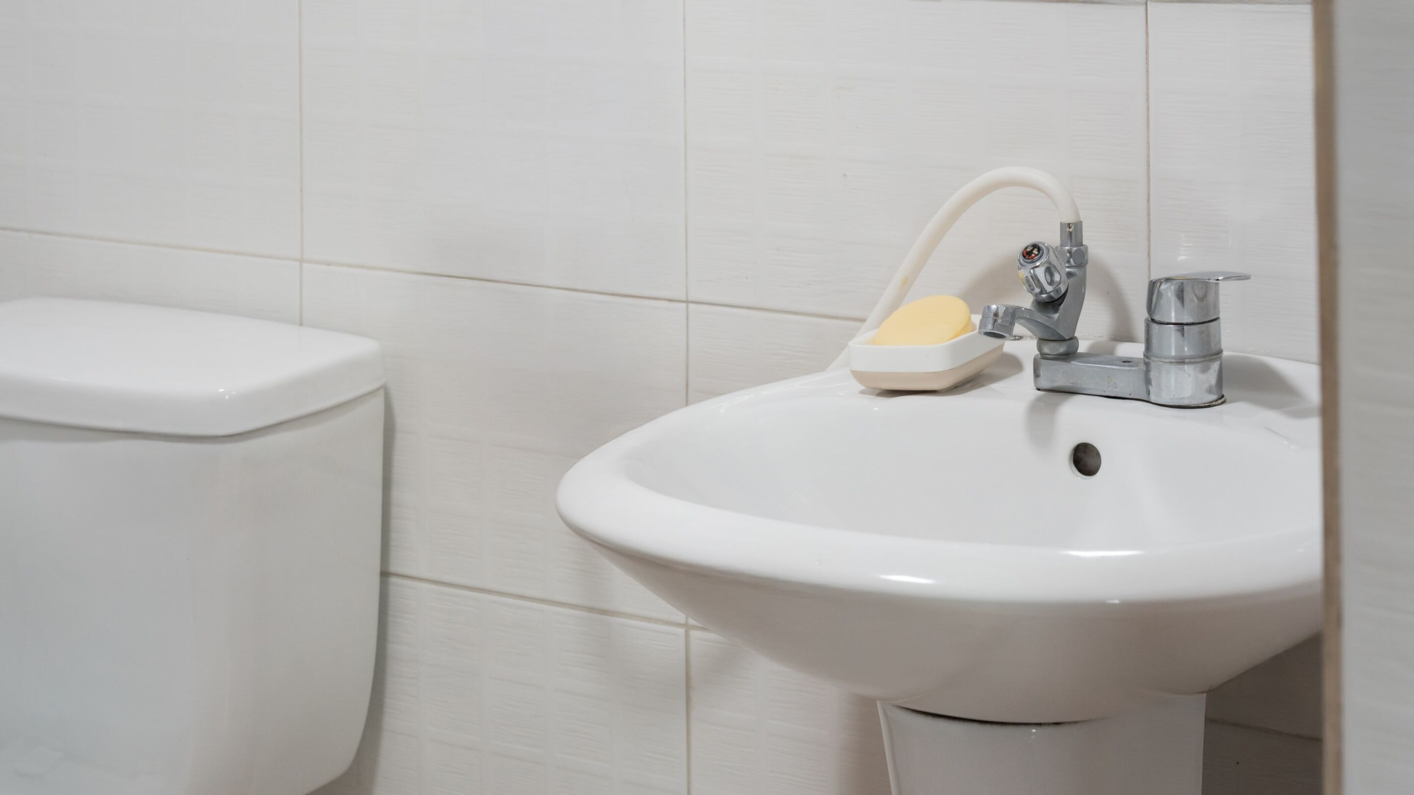 A white bathroom sink with a soap dish and a faucet.