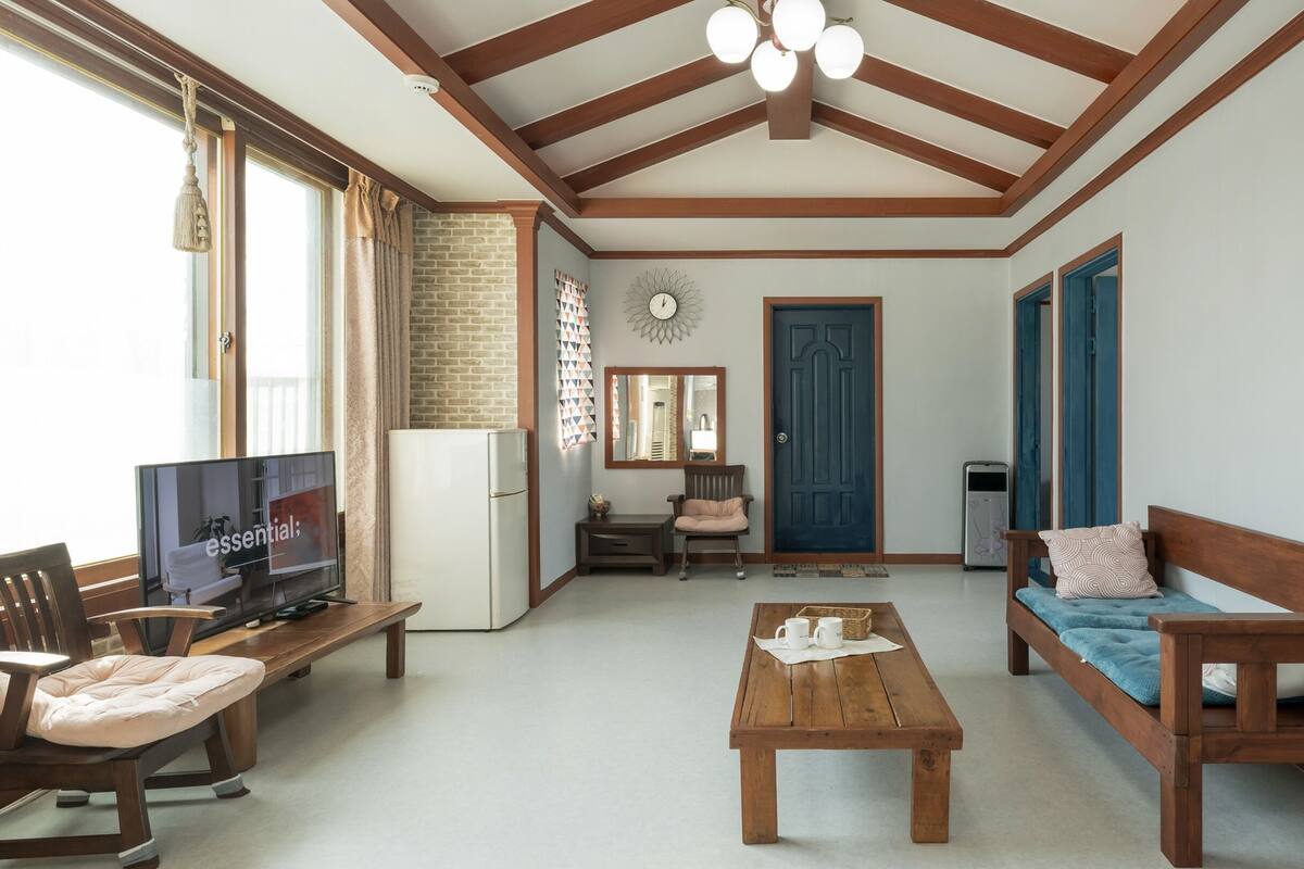 A cozy living room with a wooden bench, a sofa, a coffee table, and a TV.