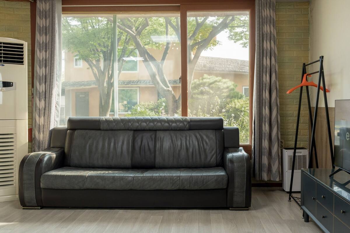 A living room with a sofa, a TV, and a window with curtains.