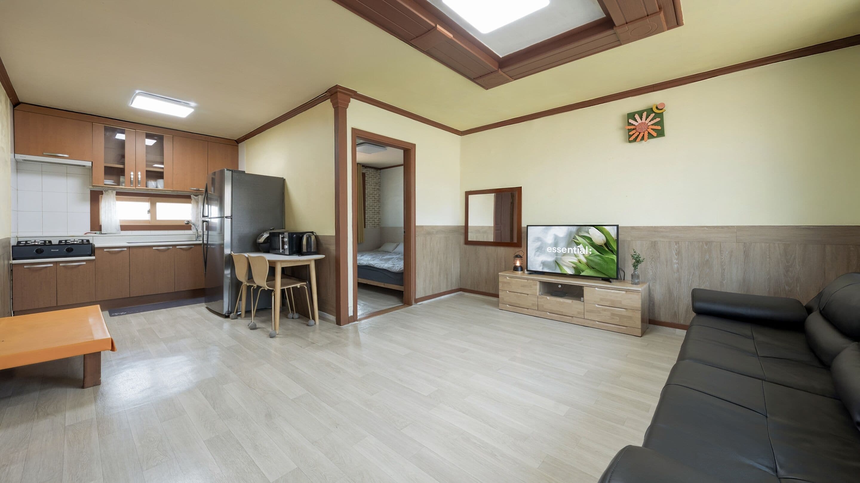 Un espacio habitable compacto con kitchenette, comedor, sofá y televisor.