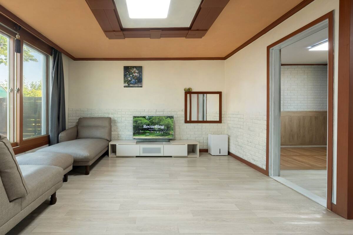 A modern living room with a sofa, a flat-screen TV, and a large window.