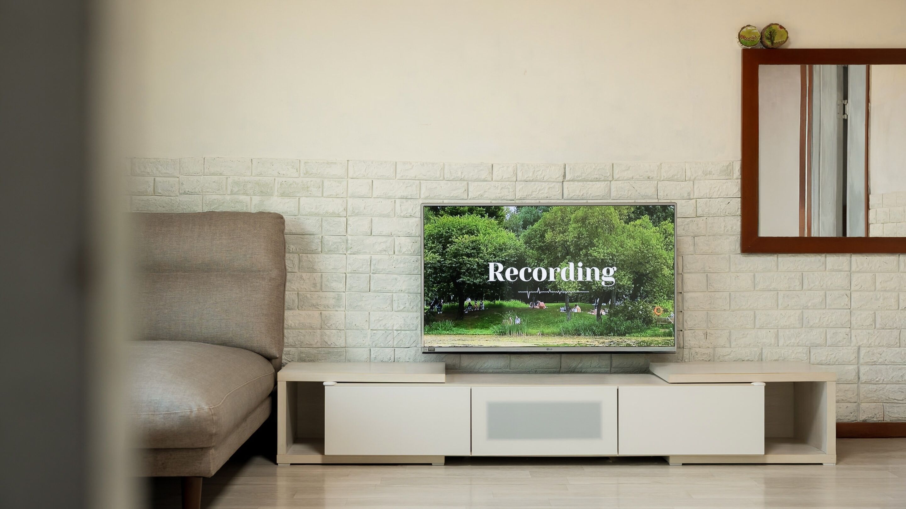 A television on a white entertainment unit with a brick wall background.