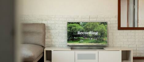 A television on a white entertainment unit with a brick wall background.