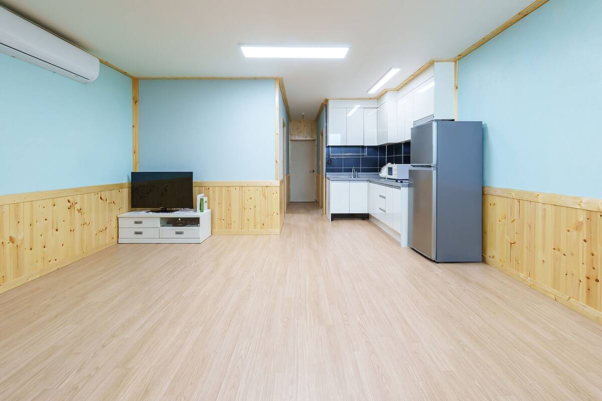 A narrow hallway with wooden paneling, a flat-screen TV, and a refrigerator.