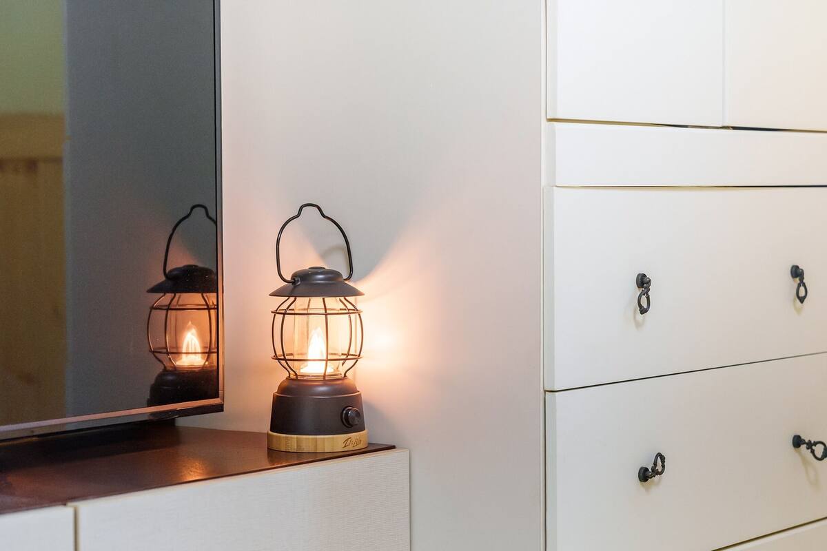 A white dresser with black handles and a mirror above it.