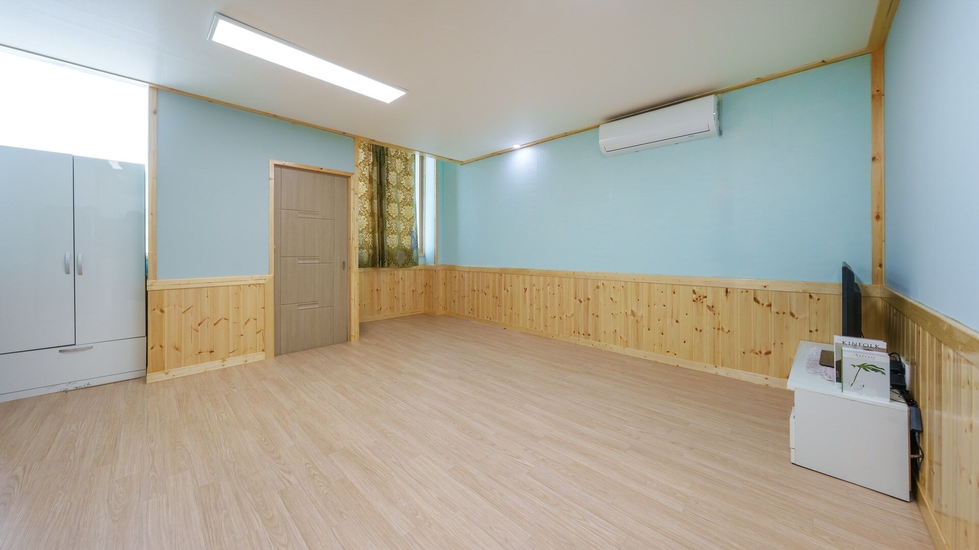 A room with wooden paneling, a wardrobe, a door, and a white appliance.
