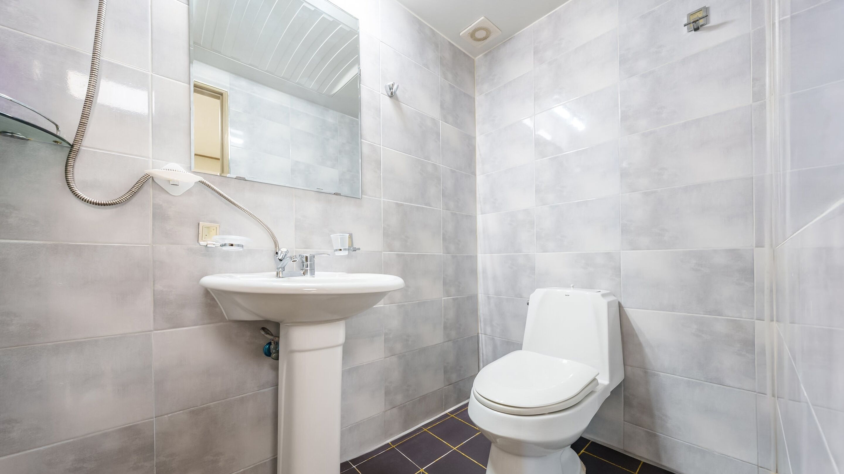 A bathroom with a white sink, toilet, and shower.