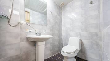 A bathroom with a white sink, toilet, and shower.