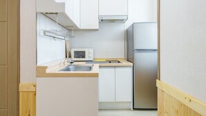 Una cucina compatta con lavandino, forno a microonde e frigorifero in acciaio inox.