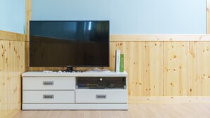 Un televisore a schermo piatto su un mobile bianco contenitore con due cassetti e un pensile con ante in vetro.