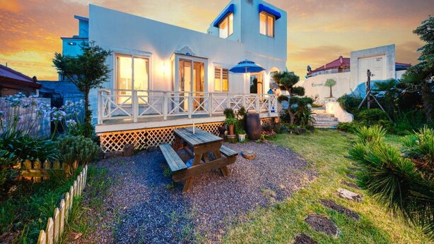 A modern two-story house with a covered patio and a gravel driveway. - Jeju Mulgogi Pension (Jeju City)