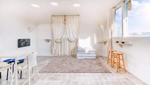 A modern room with a large window, a bed with white linens, a small table, and a chair. - Jeju Mulgogi Pension (Jeju City)