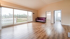 Une pièce spacieuse avec de grandes fenêtres, un canapé violet et un plancher en bois.