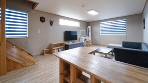 Un salon moderne avec une table en bois, un canapé, un téléviseur et un bureau.