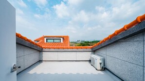 A rooftop terrace with a tiled roof, a window, and a water heater.