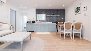 Una cocina moderna con gabinetes grises, un salpicadero negro y un comedor con sillas de mimbre blanco.