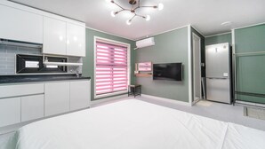 A modern kitchen with white cabinets, a black countertop, and a built-in microwave. - Samcheok Jangho Madang Minbak Pension (Samcheok)