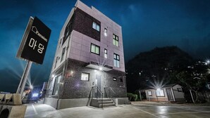 A multi-story building with a modern design, featuring a prominent sign for a pension. - Samcheok Jangho Madang Minbak Pension (Samcheok)