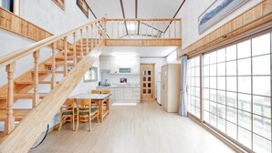 Cocina amplia con suelo de madera, comedor con sillas y una escalera que sube a un nivel superior.