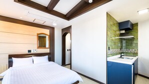 A modern hotel room with a large bed, a built-in desk with a sink, and a green-tiled backsplash in the kitchen area. - Jeju Padosoriminbak Pension (Jeju City)