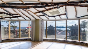 A room with large windows, wooden beams, and a view of the sea. - Jeju Padosoriminbak Pension (Jeju City)
