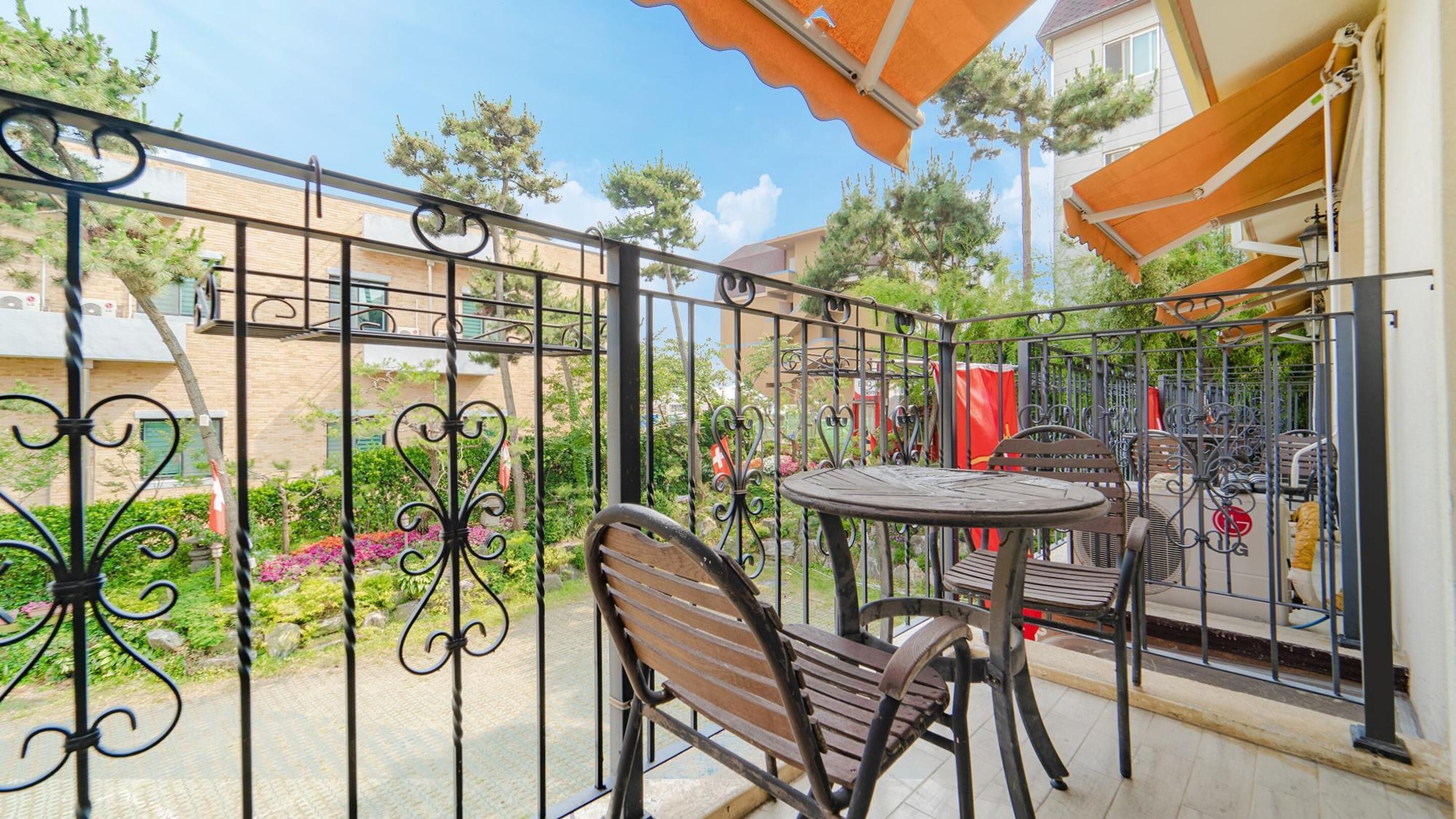 A balcony with a metal railing, a round table, and two chairs.