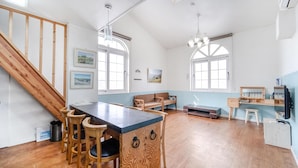 Cozinha espaçosa com piso de madeira, ilha central com banquetas e escada que leva a um andar superior.