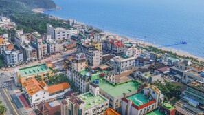 Una zona urbana costera con una combinación de edificios residenciales y comerciales, incluyendo un hotel destacado con techo verde y vistas a la playa.