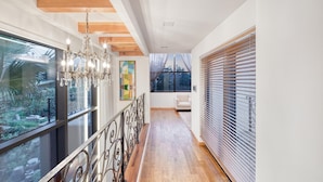 A modern interior with a wooden floor, a chandelier, a white sofa, and large windows with blinds. - Seogwipo Hanonui Achim Pensiom (Seogwipo)