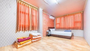 Een hotelkamer met een bed, een klein nachtkastje, een verwarming en een raam met gordijnen.