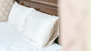 Een bed met witte beddengoed en een houten hoofdeinde.