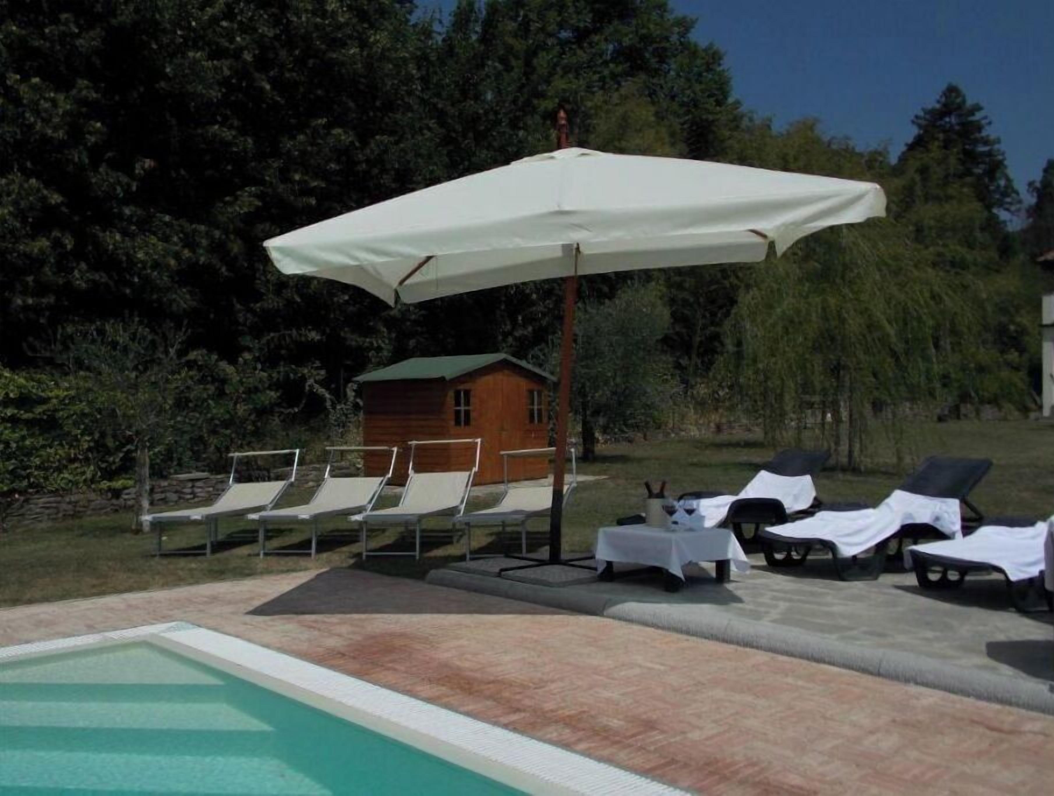 Un espace piscine avec des chaises longues et un parasol.