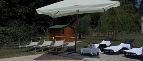 Un espace piscine avec des chaises longues et un parasol.