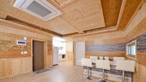 Un interior moderno con paneles de madera, una zona de cocina y un área de descanso con taburetes de bar.