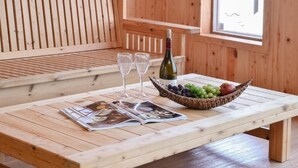 Una mesa de madera con una botella de vino, dos copas, un cuenco de fruta y una revista.