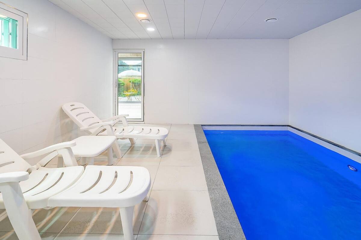 A swimming pool area with white lounge chairs and a glass door leading outside.