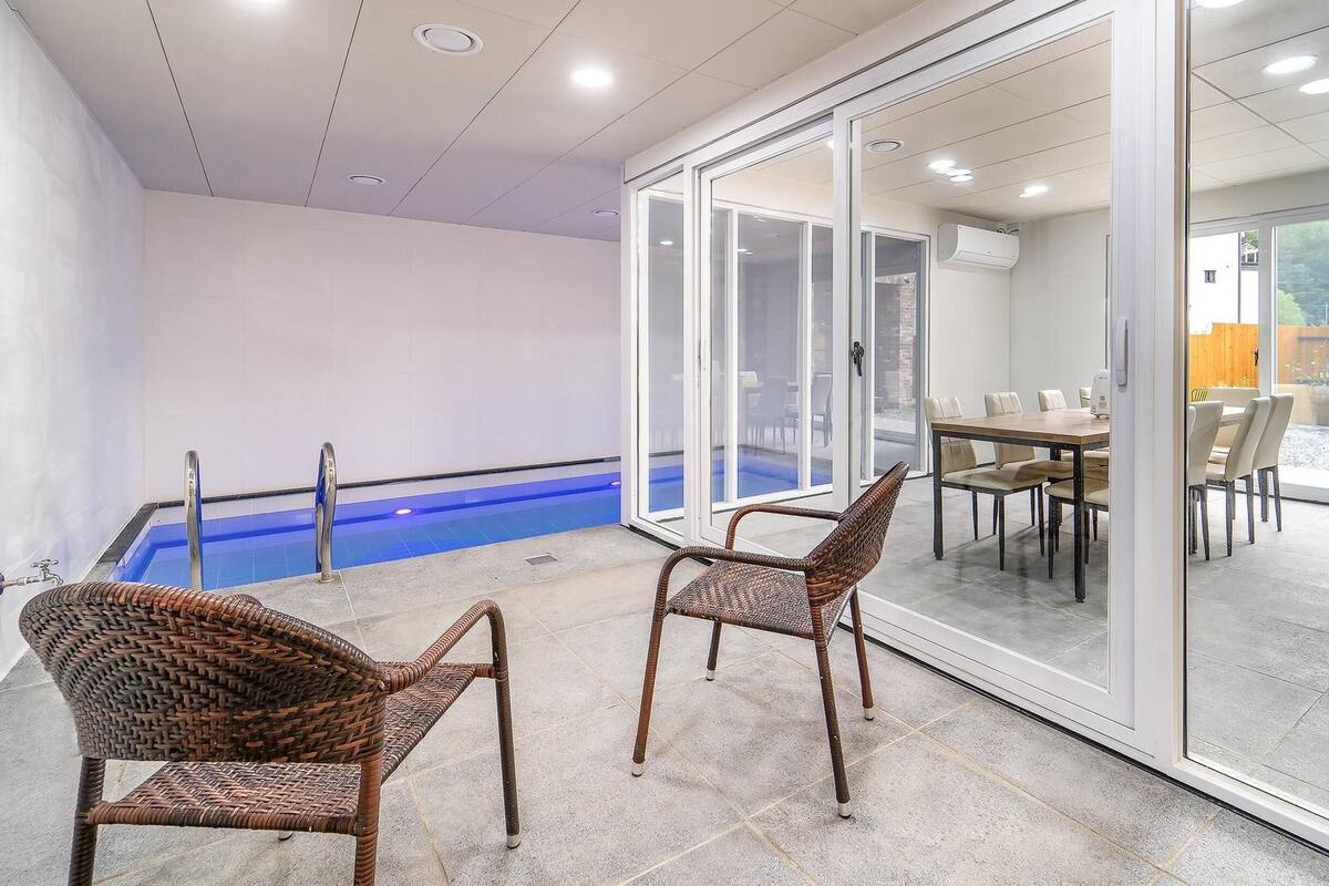 An indoor swimming pool area with a glass door leading to a dining area.