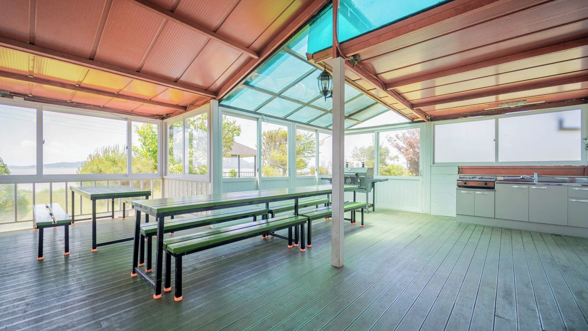 Un espace extérieur abrité avec des tables de pique-nique et un barbecue.