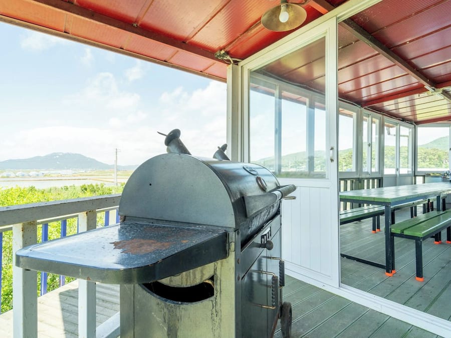 Un patio al aire libre con una parrilla, mesas y bancos, con vistas a un paisaje pintoresco.