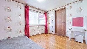 A room with a wooden floor, a bed, a desk, a door, and a window with curtains. - Ganghwa Badajeongwon Pension (Incheon)