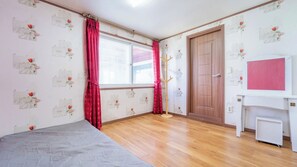 A room with a wooden floor, a bed, a desk, a door, and a window with curtains. - Ganghwa Badajeongwon Pension (Incheon)