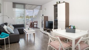 Un salon moderne comprenant un canapé, un téléviseur, une table à manger et des chaises.