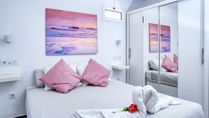Une chambre à coucher moderne avec un lit, des oreillers roses, un peignoir blanc et une rose.