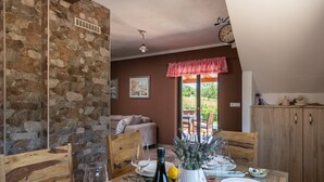 Ein Essbereich mit Steinwand, Holzsesseln, einem Tisch für vier Personen und Blick ins Freie.