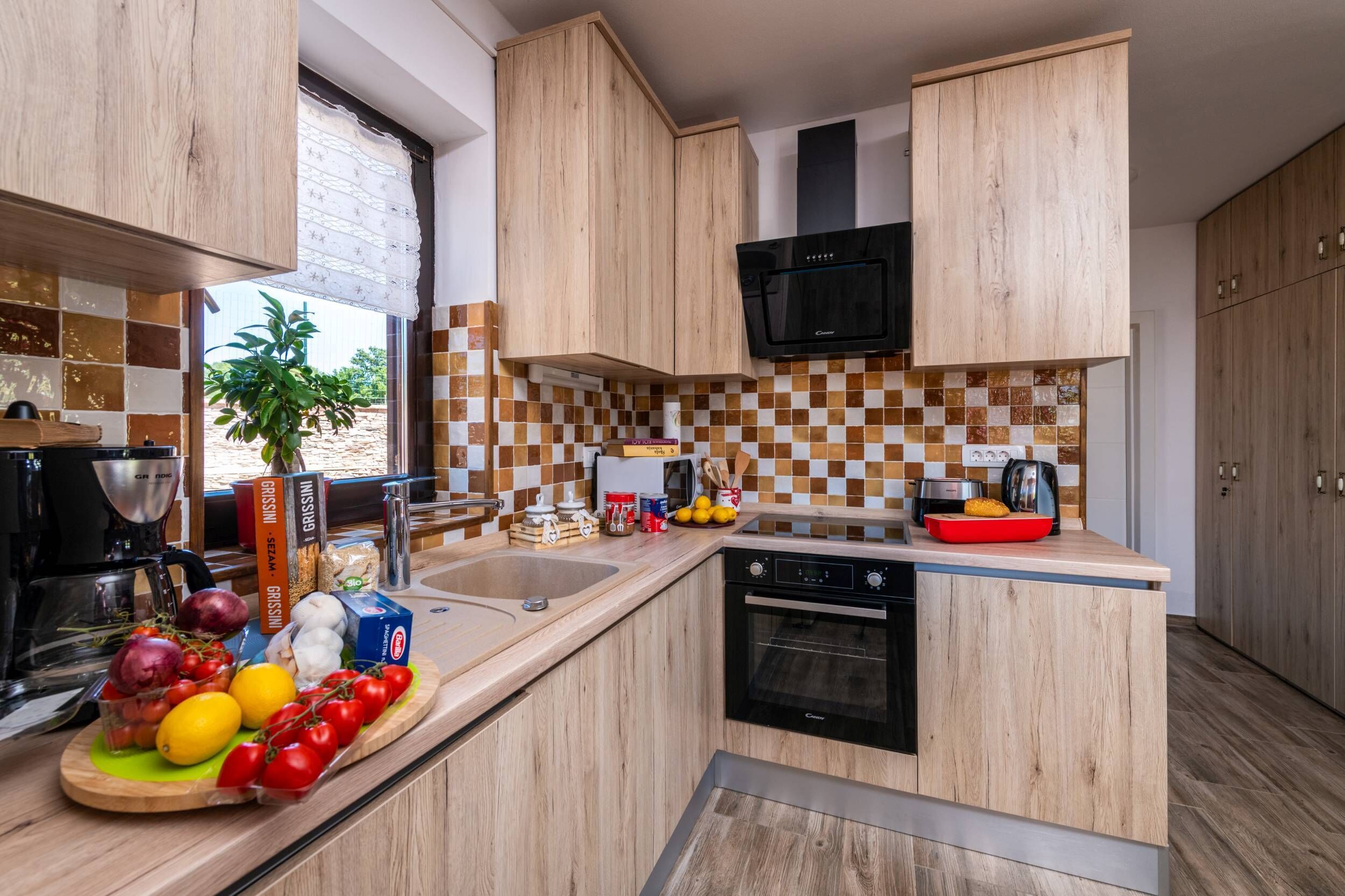 Una cocina moderna con armarios de madera, un microondas negro y un salpicadero de azulejos.