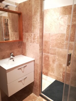 Bathroom features a single sink, two drawers, and a walk-in shower.