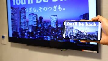 A hand holding a smartphone displaying a message "You'll be back." in front of a television screen with the same message and a cityscape background.